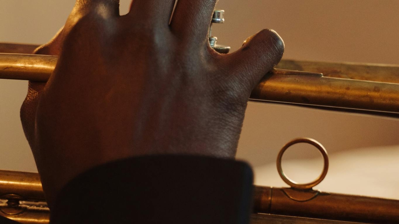 A close-up view of a musician playing a trumpet with blurred background focus.