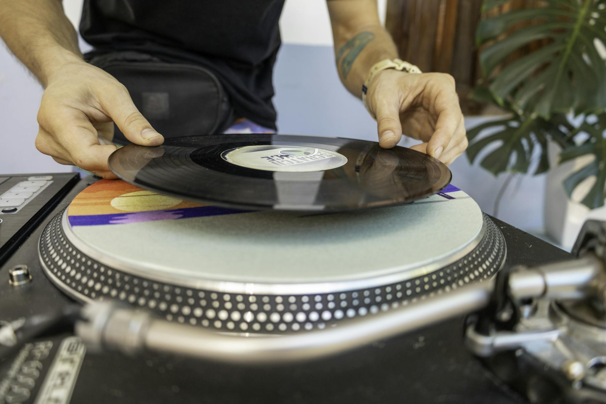DJ carefully placing a vinyl record on a turntable, highlighting the art of mixing music.